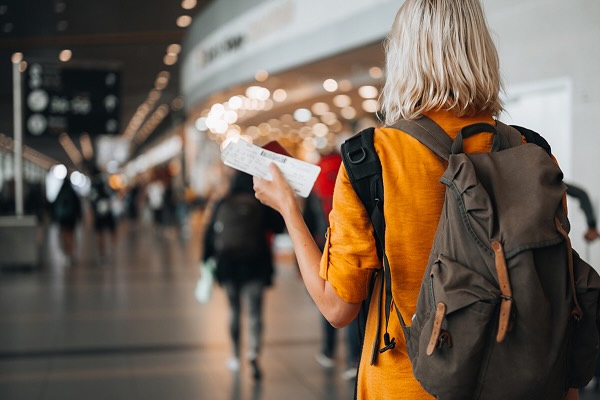 A woman at the airport holding a passport with a boarding pass